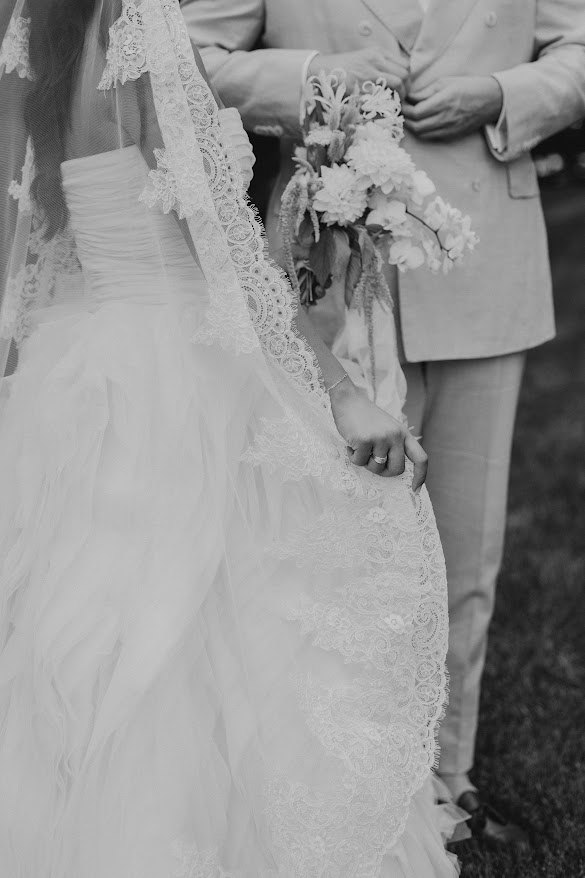 Bride in a lace veil holding her bouquet beside her partner