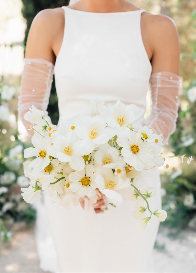 Bride in sheer gloves holding a white wildflower bouquet