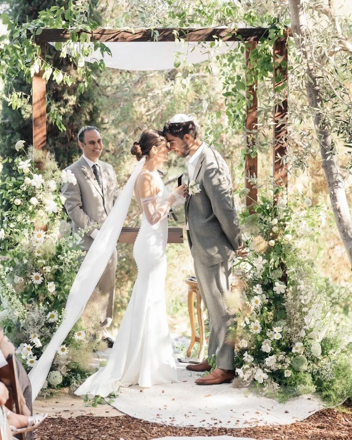 Couple at the altar beneath a floral chuppah