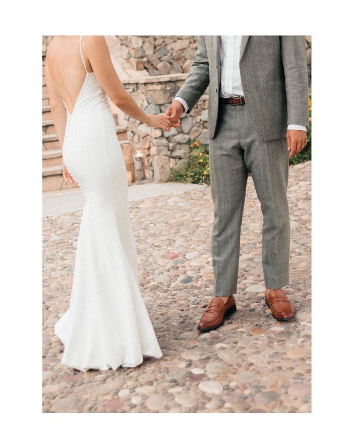 Couple holding hands in formalwear on a cobblestone courtyard