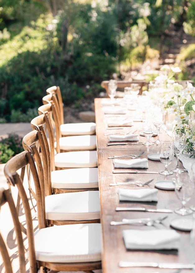Outdoor reception table set with linens and greenery